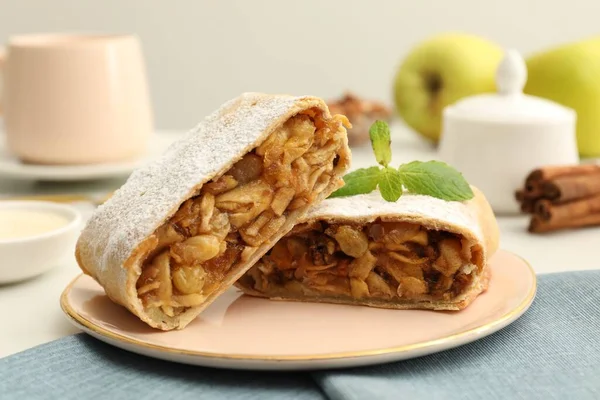 Delicious strudel with apples, nuts and raisins on table, closeup