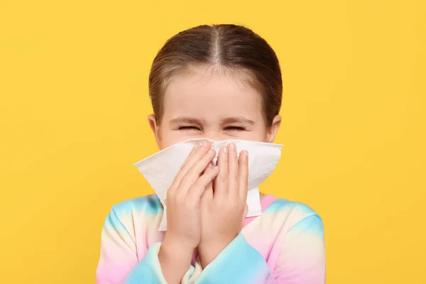 女孩在橙色背景下的组织里吹鼻涕 感冒症状 — 图库照片