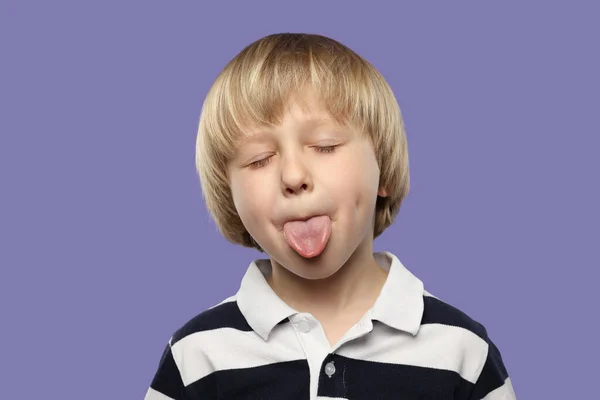 Niedliche Kleine Junge Zeigt Seine Zunge Auf Lila Hintergrund — Stockfoto