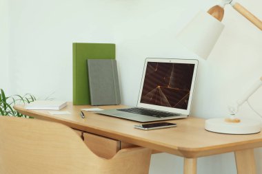 Cozy workspace with modern laptop on desk and comfortable chair at home