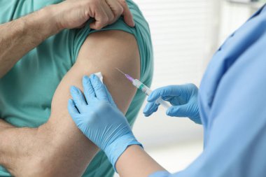 Doktor klinikteki hastaya hepatit aşısı veriyor.