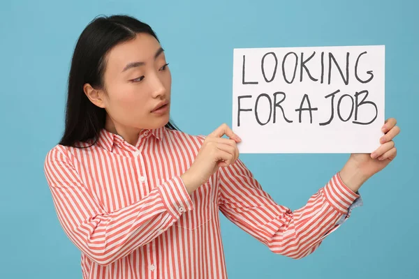 拿着标有 寻找浅蓝色背景工作 字样的失业亚洲妇女 — 图库照片
