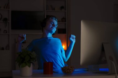 Genç çocuk geceleri yatak odasında bilgisayar kullanıyor. İnternet bağımlılığı