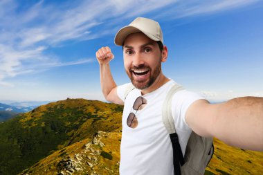 Gülümseyen adam güzel dağlarda selfie çekiyor.