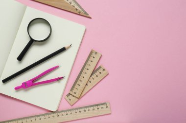 Farklı cetvel, kalem, pusula ve pembe arka planda büyüteç. Metin için boşluk