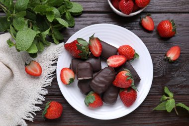 Lezzetli kremalı aperatifler, nane yaprakları ve ahşap masada taze çilekler.