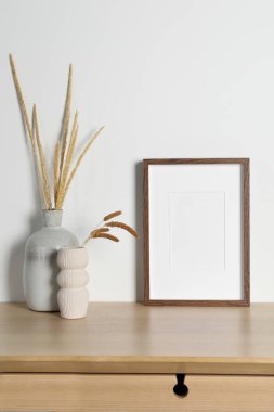 Boş fotoğraf çerçevesi ve vazolar. Ahşap masanın üzerinde kuru dekoratif çiviler var. Tasarım için model