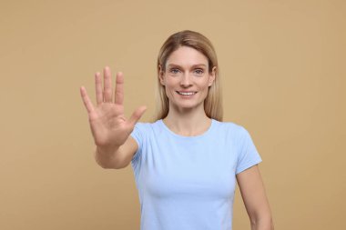 Açık kahverengi arka planda bir kadın beşlik çakıyor