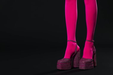 Woman wearing pink tights and high heeled shoes with platform and square toes on black background, closeup. Space for text