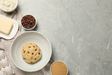 Taze hamur ve açık gri mermer masada çikolatalı kurabiye pişirmek için farklı malzemeler. Metin için boşluk