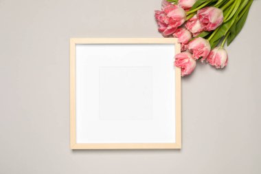 Boş fotoğraf çerçevesi ve açık gri arka planda güzel lale çiçekleri. Tasarım için model