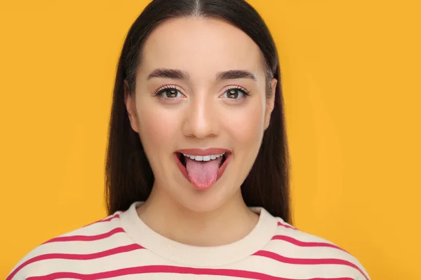 幸せな女性ショー彼女の舌上のオレンジ背景 — ストック写真