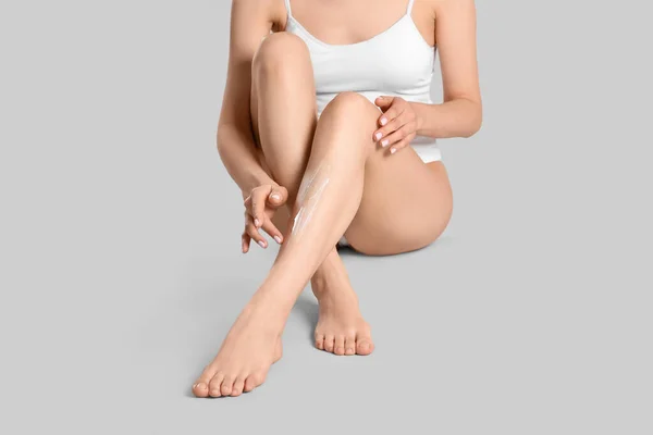 Açık Gri Arka Planda Pürüzsüz Bacaklarına Vücut Kremi Süren Kadın — Stok fotoğraf