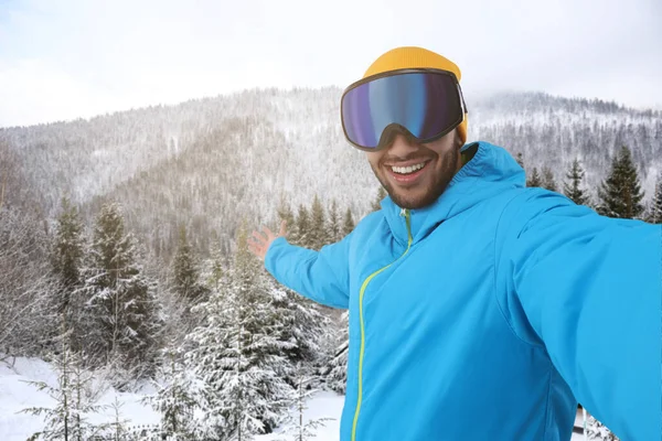 Leende Ung Man Skidglasögon Tar Selfie Snöiga Berg — Stockfoto