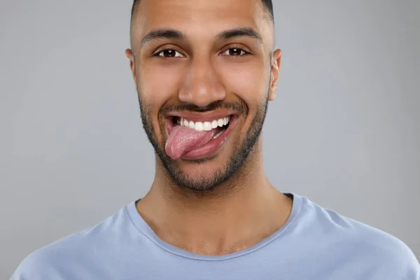 明るい灰色の背景に彼の舌を示す幸せな若い男 — ストック写真