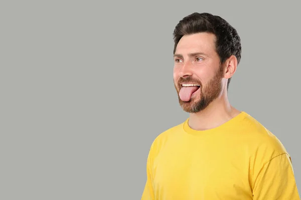 男は灰色の背景に彼の舌を示す テキストのためのスペース — ストック写真