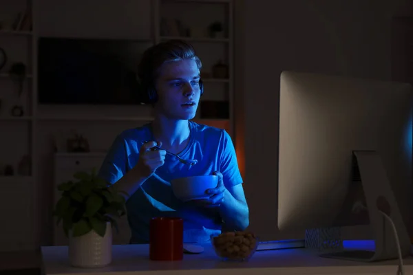 夜はパソコンを使いながら10代の男の子がお粥を食べる インターネット中毒 — ストック写真