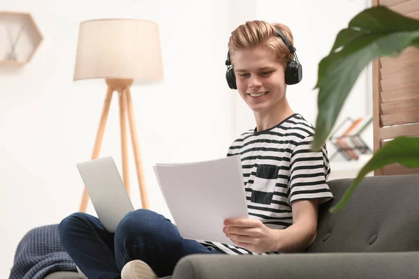 stock image Online learning. Smiling teenage boy with laptop looking on essay at home