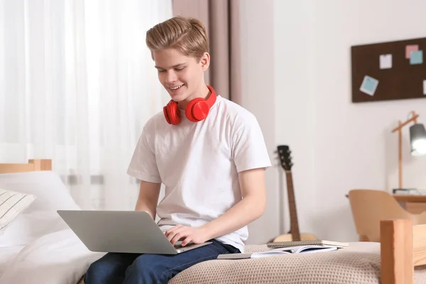 stock image Online learning. Smiling teenage boy typing on laptop at home