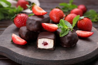 Delicious glazed curd snacks, mint leaves and fresh strawberries on wooden table, closeup