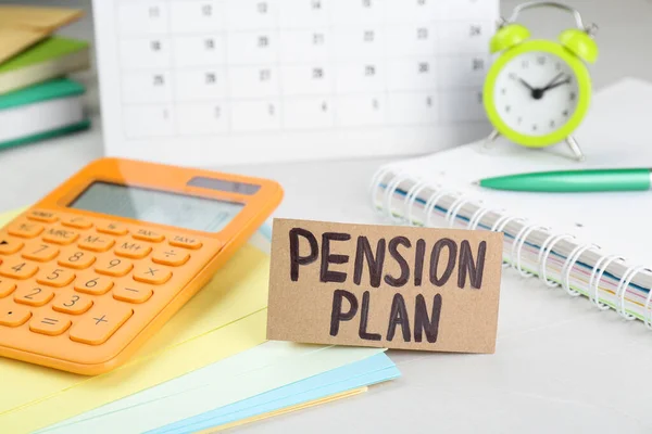 Card with words Pension Plan, calculator and stationery on white office table, closeup