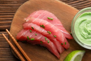 Lezzetli sashimi (taze çiğ ton balığı parçaları) wasabi sosu ve ahşap tahtada limon dilimi ile servis edilir.