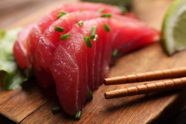 Lezzetli sashimi (yeşil soğanlı taze çiğ ton balığı parçaları) ve ahşap tahta çubuklar, yakın plan
