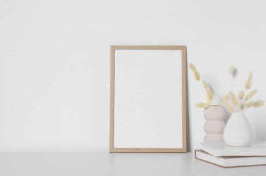 Boş fotoğraf çerçevesi ve beyaz masa üzerinde kuru dekoratif çiviler olan vazolar. Tasarım için model
