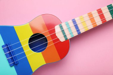 Pembe arka planda renkli ukulele, üst manzara. String müzik aleti