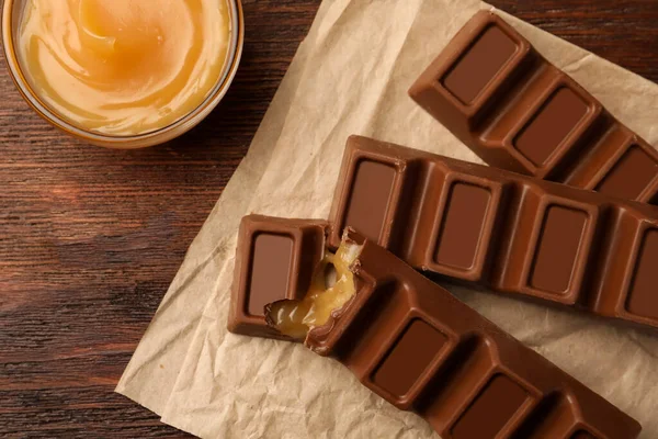 Smaklig Choklad Barer Och Skål Med Karamell Träbord Platt Låg — Stockfoto