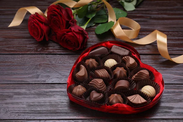 Herzförmige Schachtel Mit Leckeren Schokoladenbonbons Rosen Und Schleife Auf Dem — Stockfoto