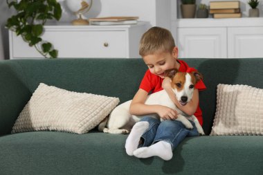Evdeki kanepede tatlı köpeğiyle küçük bir çocuk, mesaj atmak için yer var. Sevimli hayvan.