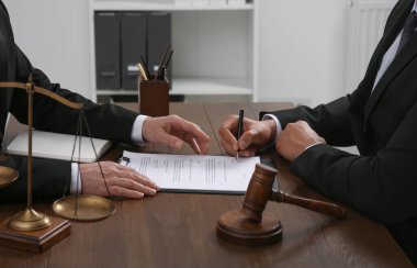 Hukuk ve adalet. Ofisteki ahşap masada evraklarla çalışan avukatlar, yakın plan.
