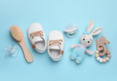 Flat lay composition with pacifiers and other baby stuff on light blue background