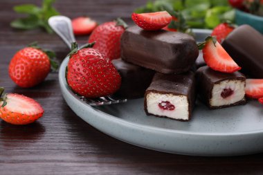 Delicious glazed curd snacks, mint leaves and fresh strawberries on wooden table, closeup