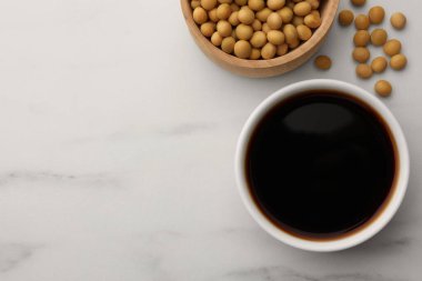 Soya sosu kasede ve soya fasulyesi beyaz mermer masada, düz yerde. Metin için boşluk