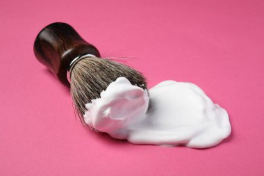 Pembe arka planda tıraş köpüğü ile fırça, yakın plan