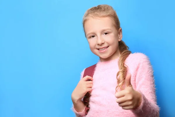ライトブルーの背景に親指を示すバックパックを持つ幸せな女の子 テキストのスペース — ストック写真