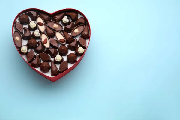 Hartvormige Doos Met Heerlijke Chocolade Snoepjes Lichtblauwe Achtergrond Bovenaanzicht Ruimte — Stockfoto