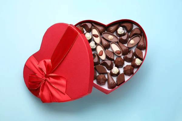 Hjärtformad Låda Med Läckra Choklad Godis Ljusblå Bakgrund Ovanifrån — Stockfoto