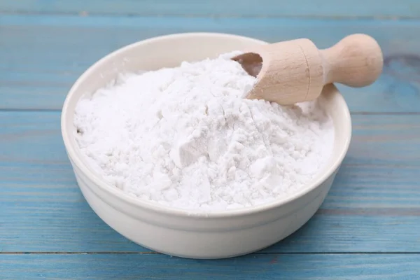 stock image Bowl and scoop of natural starch on light blue wooden table, closeup