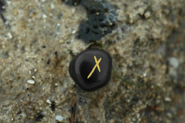 stock image Black rune Nauthiz on stone outdoors, closeup