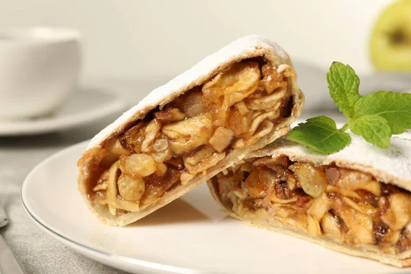 Delicious strudel with apples, nuts and raisins on plate, closeup