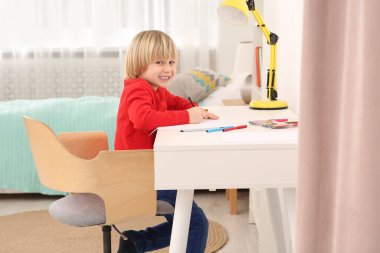Odadaki masada resim yapan küçük çocuk. Ev işyeri