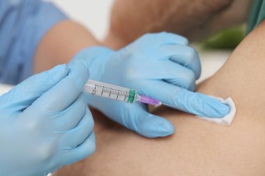 Doktor beyaz arka plandaki hastaya hepatit aşısı yapıyor.