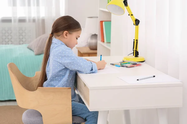 かわいい女の子が部屋に机の上にマーカーで描画します ホームワーク — ストック写真
