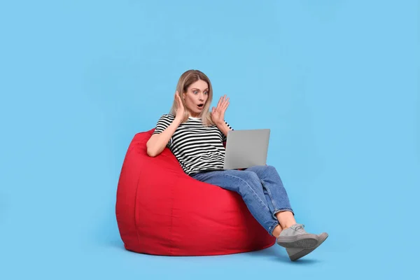 Emotionale Frau Mit Laptop Auf Sitzsack Stuhl Vor Hellblauem Hintergrund — Stockfoto
