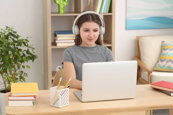 部屋のデスクでノートパソコンとヘッドフォンを使用してかわいい女の子 ホームワーク — ストック写真