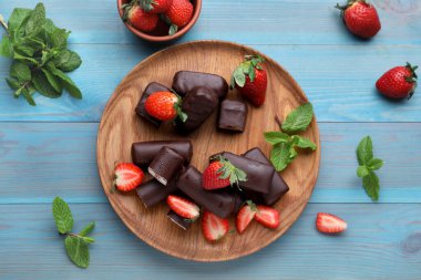 Lezzetli kremalı aperatifler taze çilek ve açık mavi ahşap masa üzerinde nane, düz uzanmış