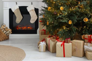 Noel ağacının altında bir sürü farklı hediye kutusu ve oturma odasında şenlikli bir dekor.